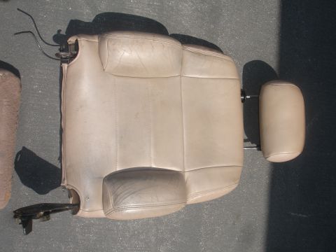 1993 Ford Taurus - A detached tan leather car seat with a separate headrest lies on a dark surface.