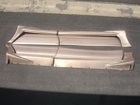 1993 Ford Taurus - Several car body side trim pieces are laid out on a dark surface, possibly for sale or storage.