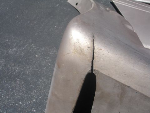 1993 Ford Taurus - A cracked silver bumper part is shown close-up against a dark asphalt background.