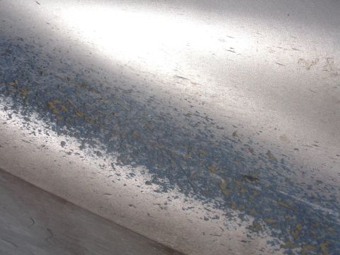 1993 Ford Taurus - Peeling paint reveals layers of color on a metallic surface, possibly a car part.