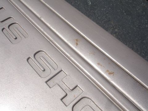 1993 Ford Taurus - Close-up of a silver SHO emblem, showing some rust spots on the textured surface.