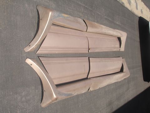 1993 Ford Taurus - Two brown car door trim pieces are laid out on a dark surface. The trim pieces have a curved end and embossed horizontal lines.