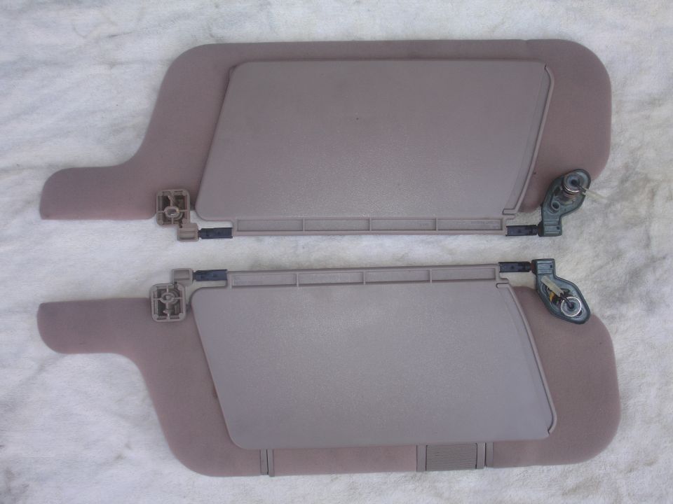 Two beige car sun visors with metal pivot brackets