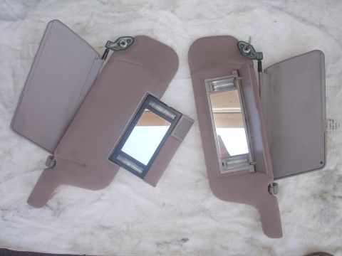 1993 Ford Taurus - A pair of beige sun visors with illuminated vanity mirrors are displayed against a light-colored background.