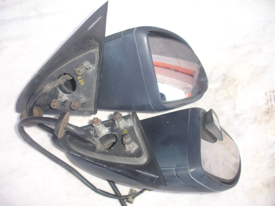 Two dark gray side view mirrors, one slightly behind the other, showing mounting hardware and wiring
