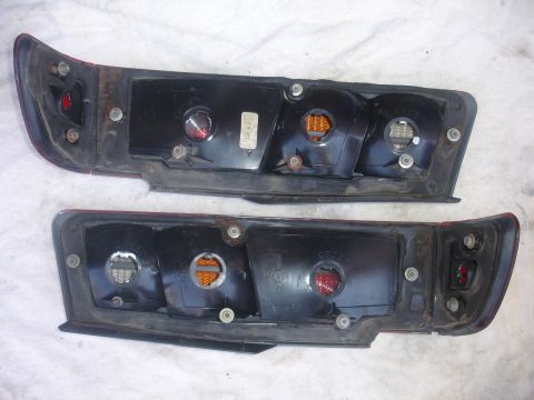 1993 Ford Taurus - The rear view of two car taillights, revealing their internal components and mounting hardware.