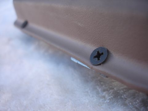 1993 Ford Taurus - A tan plastic trim panel is secured with two black screws, showing a textured surface.