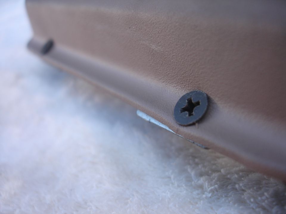 Close-up of a tan interior trim piece held by two screws