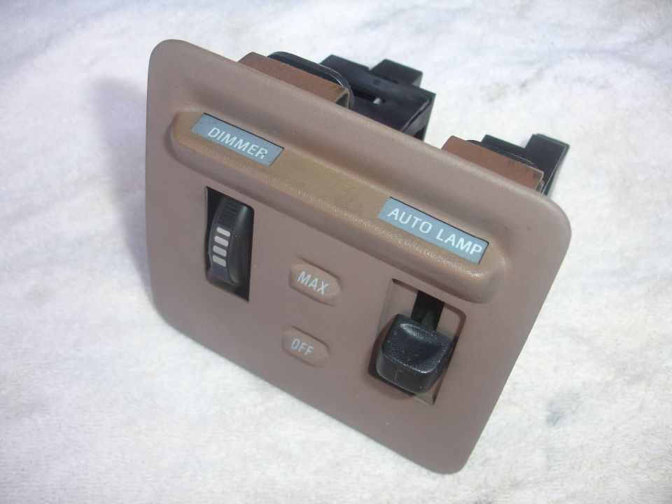 Tan plastic light switch panel with "DIMMER" and "AUTO LAMP" labels, and slider controls