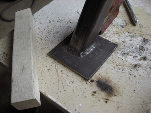 1993 Ford Bronco - Metal bracket welded to a square base sits on a workbench surface.