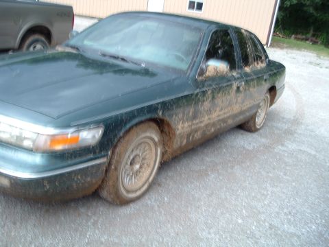 1995 Mercury Grand Marquis - This 1995 Mercury Grand Marquis is heavily caked in mud, suggesting recent off-road or adverse weather conditions.