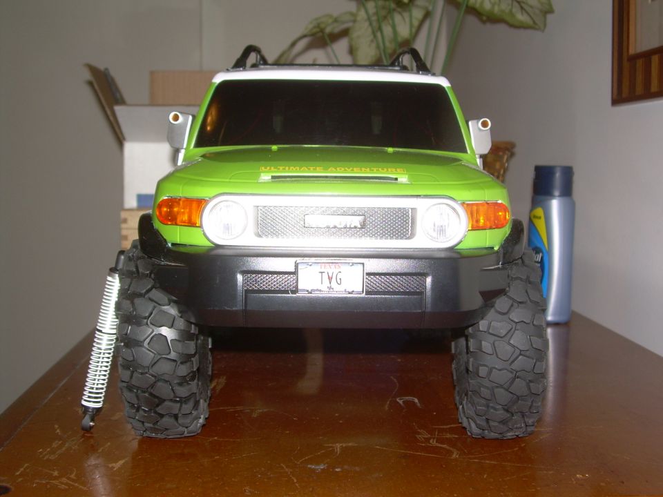 green toy remote control truck with big tires, front view