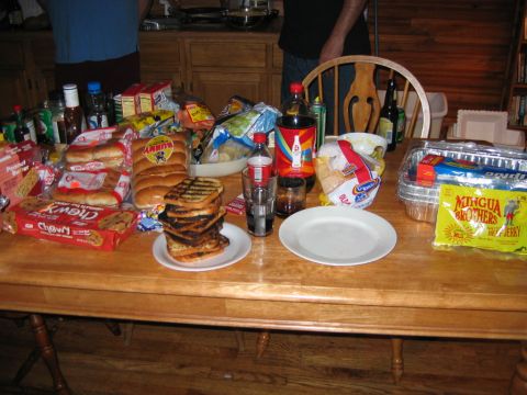 1985 Ford LTD Crown Victoria - A table is set with various food items including hot dogs, buns, cookies, and beverages, suggesting a meal or gathering.