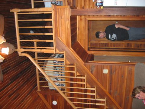 1985 Ford LTD Crown Victoria - A man rests inside a wooden structure while a staircase and a portion of another person are visible.