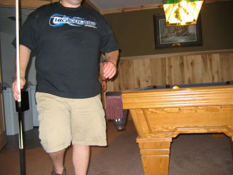 1985 Ford LTD Crown Victoria - A man stands with a pool cue in a room with a pool table and a framed picture on the wall.