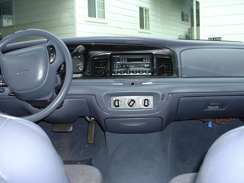 Gray interior dashboard and steering wheel of a Ford sedan with center stack and radio