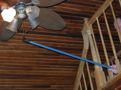 1985 Ford LTD Crown Victoria - A blue pole is extended towards a ceiling fan, with a wooden staircase in the background.