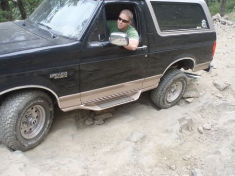 1996 Ford Bronco - A man drives a black and tan 1996 Ford Bronco over a rocky path.