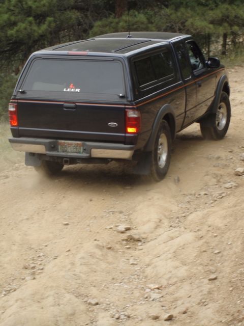 1996 Ford Bronco - Ford Ranger pickup truck with Leer cap on a dirt road.
