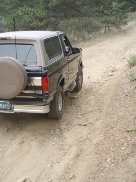 1996 Ford Bronco - The 1996 Ford Bronco navigates a dusty, unpaved road, kicking up dirt as it goes.