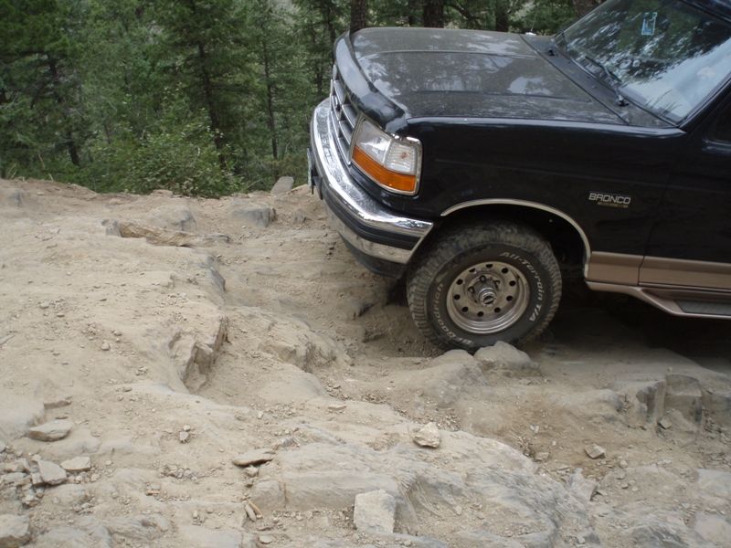 Black Ford Bronco on rocky terrain. Chrome bumper, tan lower body trim, and 'Bronco' badge visible
