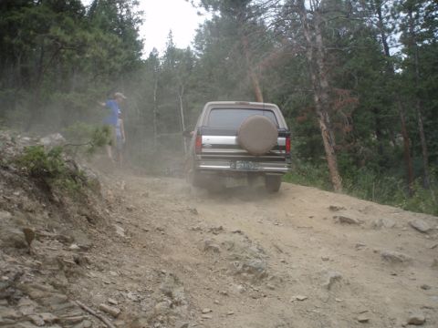 1996 Ford Bronco - This 1996 Ford Bronco is navigating a challenging dirt road in a wooded area.