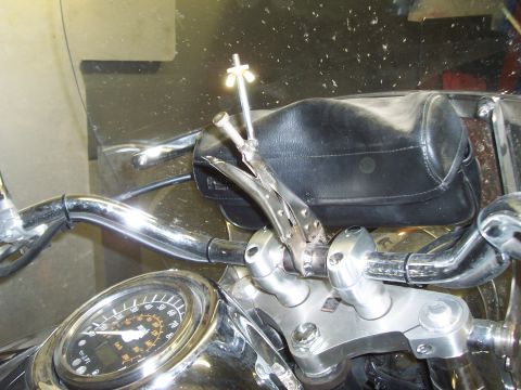 1994 Ford F-150 - A vise grip is clamped onto the handlebars of a motorcycle, holding a small metal rod.
