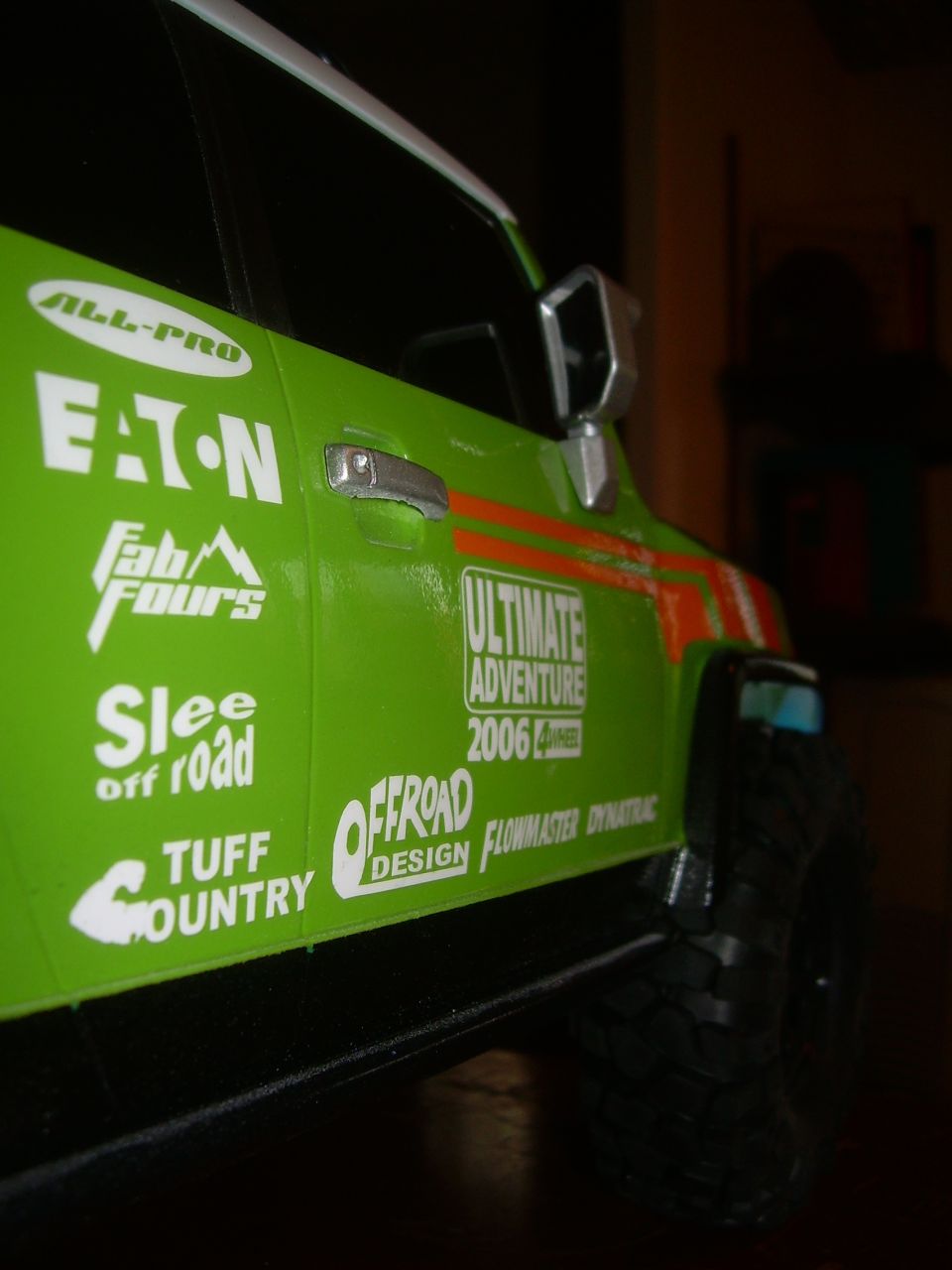 Green toy truck with 'Ultimate Adventure 2006' decal and various off-road brand stickers on the side