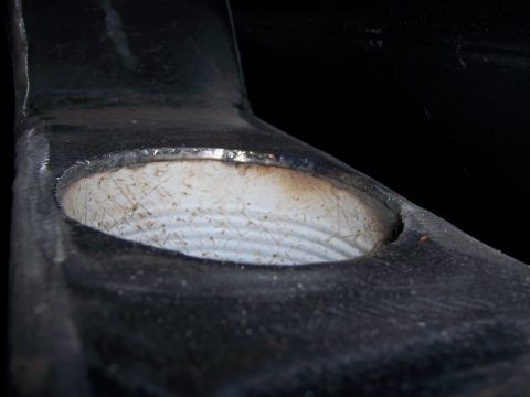 1991 Ford Bronco - Detail of a metal bracket with a threaded opening, likely a component from a vehicle's chassis or suspension system.