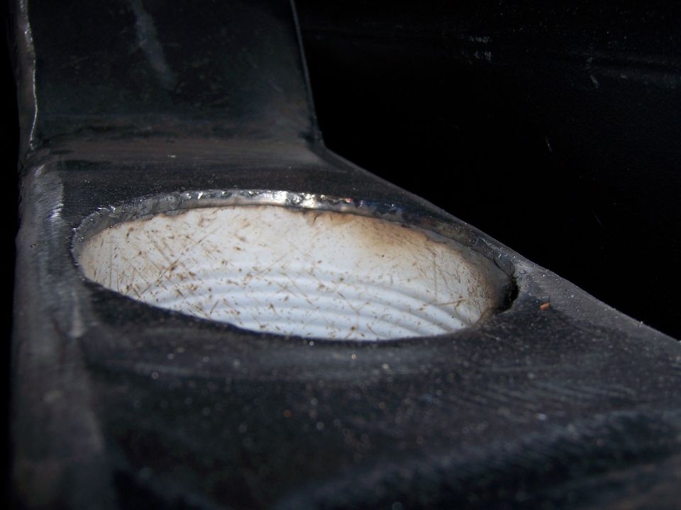 Close-up of a black metal bracket with a circular opening showing internal threads