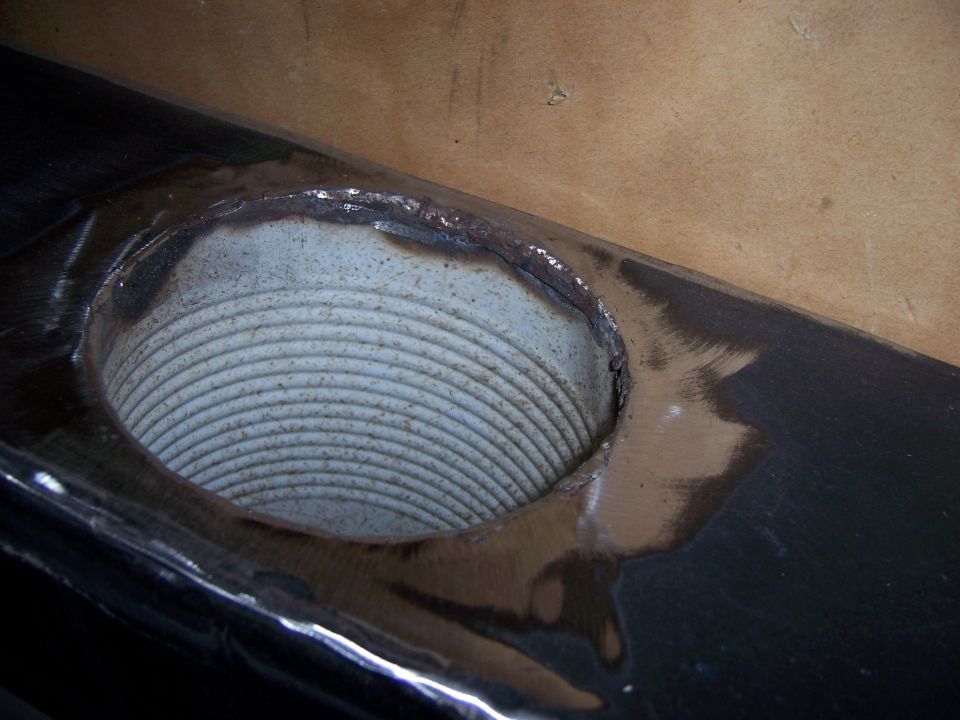 Close-up of a metal part with a ribbed opening, showing weld marks around the edge