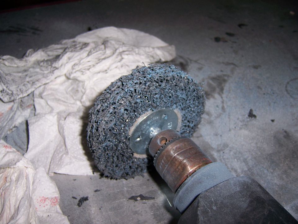 Wire wheel attachment on a drill, next to some crumpled paper towels