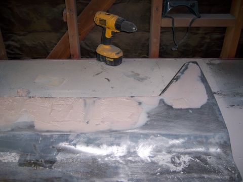 1991 Ford Bronco - A car door panel is being worked on, with body filler applied and a drill nearby.
