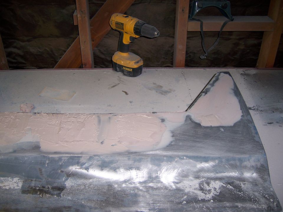 Car door panel with body filler and a yellow Dewalt drill on a workbench