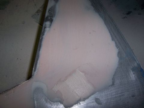 1991 Ford Bronco - Body filler is being applied to a metal panel, indicating auto body repair work is in progress.
