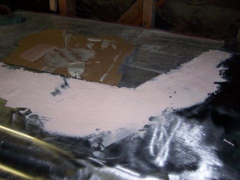 1991 Ford Bronco - Body filler is being applied to a metal panel, likely for repair or modification.