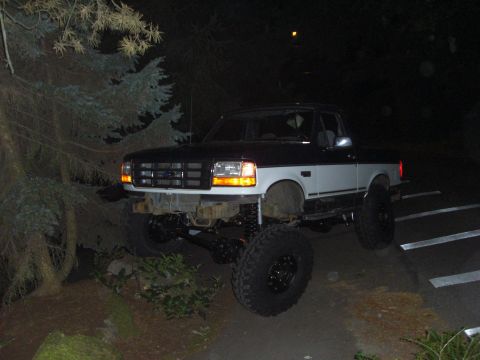 1993 Ford Bronco - A modified Ford F-Series truck with a lifted suspension and oversized tires is seen at night.