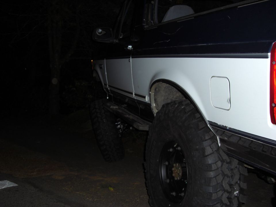Rear quarter view of a white and black 1993 Ford Bronco with large off-road tires