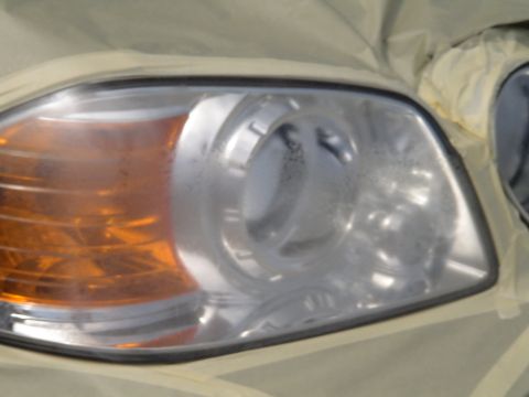 1993 Ford C-350 (Centurion Conversions) - A car headlight assembly, partially covered with masking tape, is shown up close.