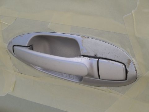 1993 Ford C-350 (Centurion Conversions) - A close-up of a silver car door handle shows wear and tear, with masking tape applied around it.