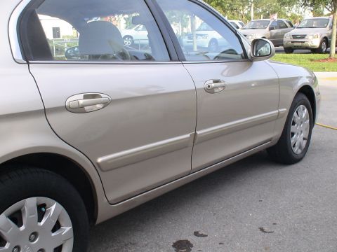 1993 Ford C-350 (Centurion Conversions) - Side profile of a tan sedan with other cars in the background.