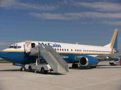 2000 Ford Crown Victoria - A commercial airplane with 'McCain Express' branding is parked on the tarmac, with a service truck and stairs attached.