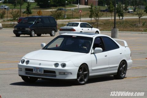 1994 Acura Integra - A white 1994 Acura Integra sedan is captured in a three-quarter front view, a sunroof and dark aftermarket wheels.
