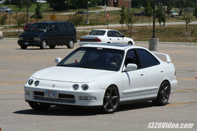 White lowered Acura Integra sedan on bronze wheels with rear wing in a parking lot