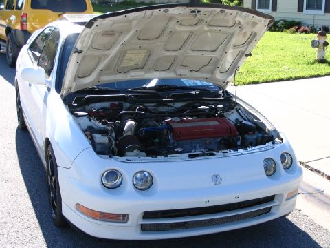 1994 Acura Integra - The front of a white Acura Integra is shown with its hood open, revealing the engine bay.
