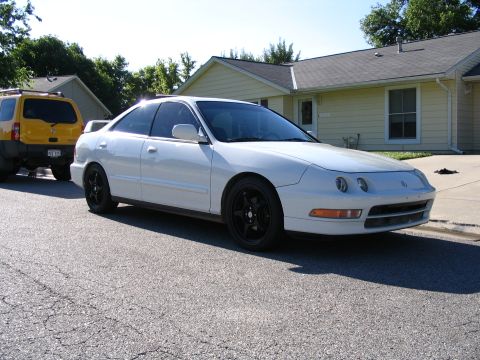 1994 Acura Integra - A white 1994 Acura Integra coupe is parked on a street next to a yellow SUV.