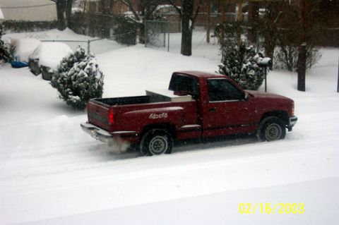 1991 Ford Crown Victoria LTD - A red pickup truck navigates through a snowy landscape, kicking up snow as it drives.