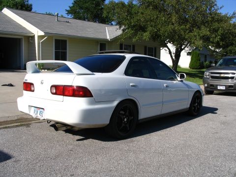 1994 Acura Integra - White 1994 Acura Integra sedan with a rear spoiler and black wheels parked outside a house.