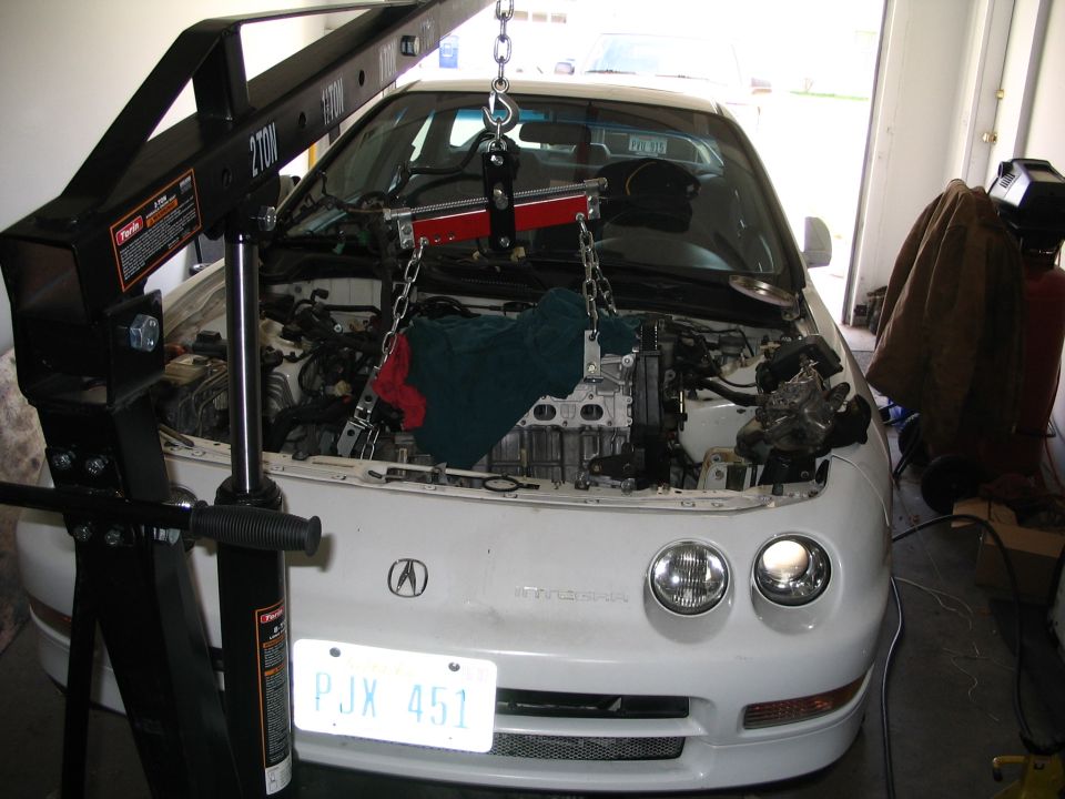 White Acura Integra with engine hoist over open bay during engine swap