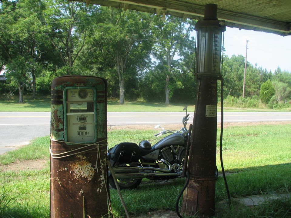 Motorcycle parked between two vintage gas pumps